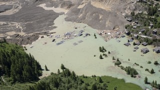 Water from the Lonza river flows over the mud and stone, to form of a lake flooding the last houses of the village of Blatten, Switzerland, Friday, May 30, 2025. A large part of the village of Blatten, located in the Loetschental Valley in the canton of V