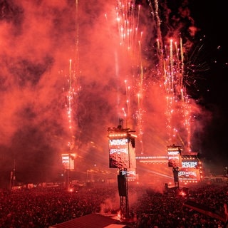 Ein rotes Feuerwerk bei Rock am Ring. Auf den LED-Leinwänden wird Linkin Park als Headliner 2026 bekannt gegeben.